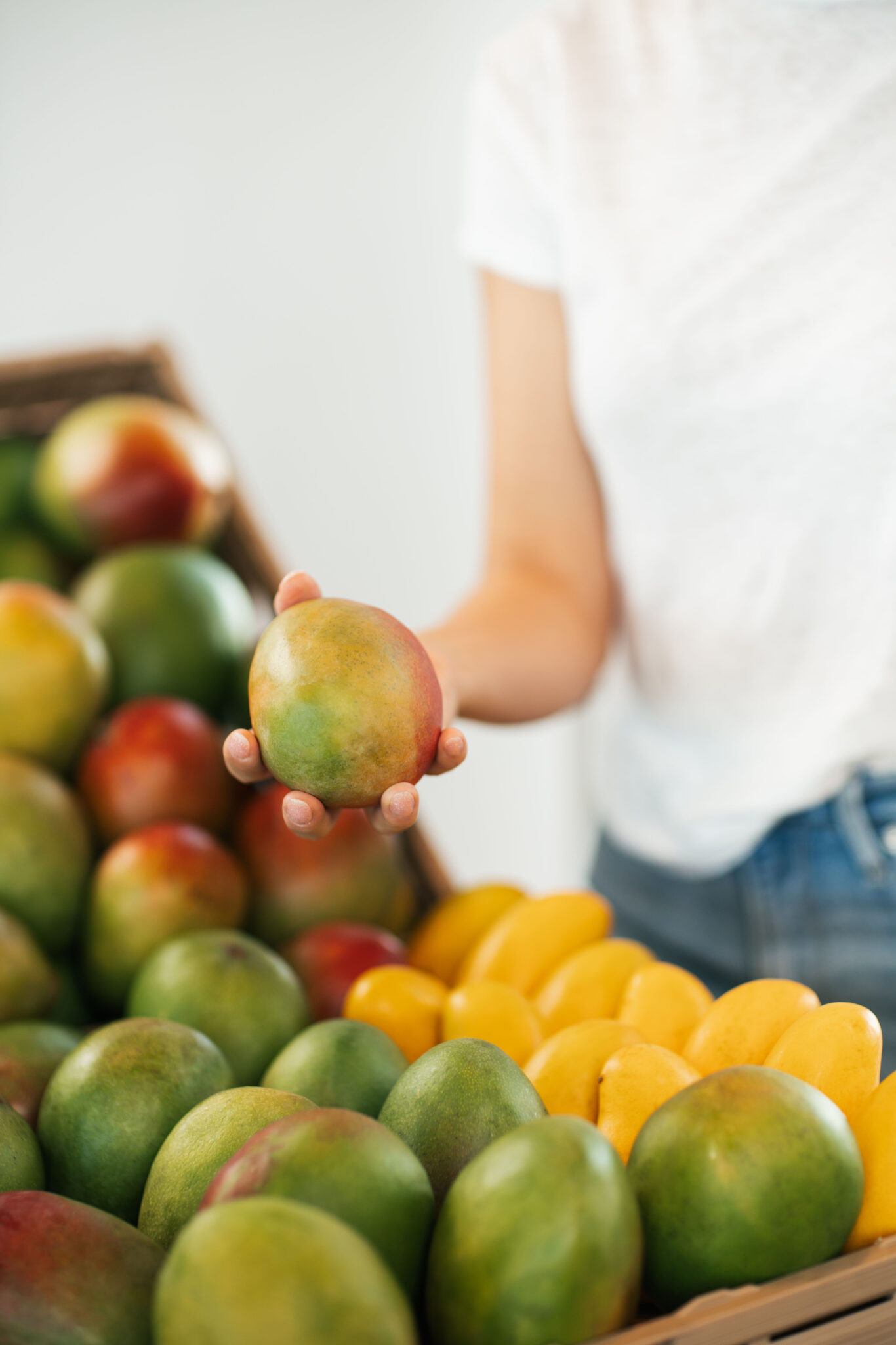 Person Choosing Mango from a Mango Display